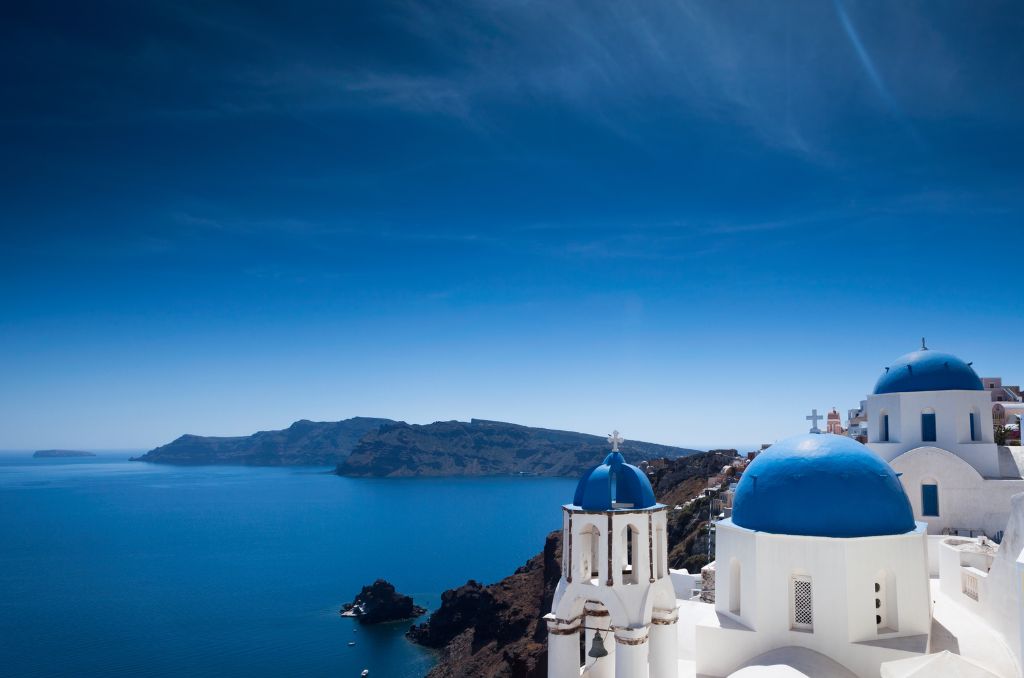 Weiße Gebäude mit blauen Kuppeln in Oia auf Santorin, gelegen an einer Steilküste über dem tiefblauen Ägäischen Meer. Weiße Gebäude mit blauen Kuppeln in Oia auf Santorin, gelegen an einer Steilküste über dem tiefblauen Ägäischen Meer.
